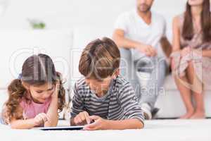 Brother and sister using tablet pc together on floor