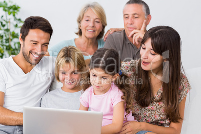 Smiling family watching something on laptop