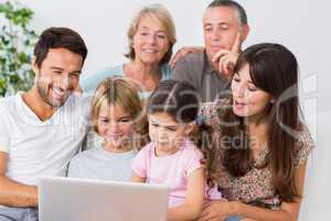 Smiling family watching something on laptop