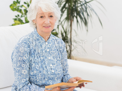 Elderly cheerful woman reading a old novel
