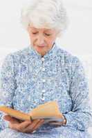 Elderly focused woman reading a old novel