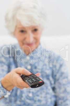 Elderly cheerful woman using the remote