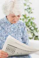 Elderly focused woman reading newspapers