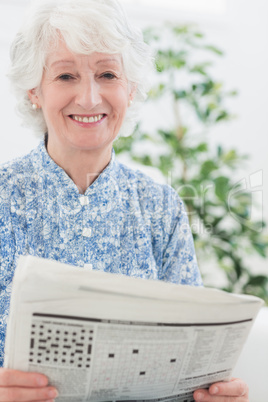 Elderly smiling woman reading newspapers