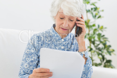 Elderly woman reading papers on the phone