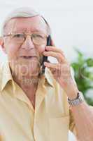 Smiling elderly man calling someone