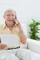 Elderly smiling man reading papers on the phone
