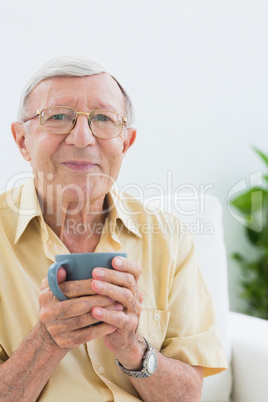 Elderly man looking at camera with a cup