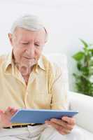 Elderly focused man using a digital tablet