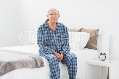 Aged man sitting on his bed