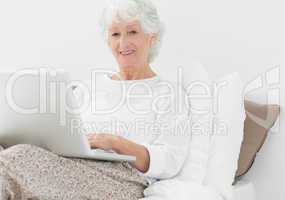 Smiling elderly woman typing on her laptop