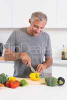 Cheerful man cutting a yellow pepper