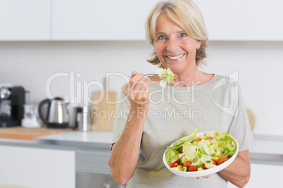 Smiling woman eating salad