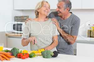 Smiling couple cutting vegetables together