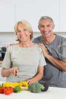 Cheerful couple cutting vegetables together