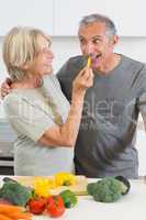 Smiling husband tasting a slice of yellow pepper
