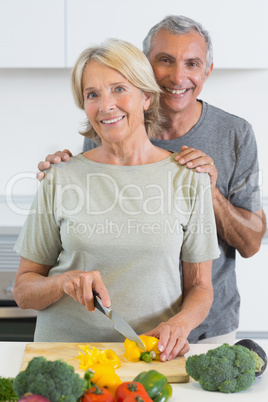 Joyful couple cutting a pepper