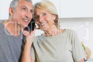 Cheerful mature couple listening a call together