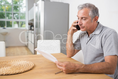 Man calling and reading a sheet of paper