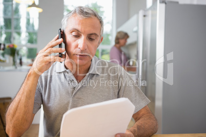 Focused man calling with a sheet of paper