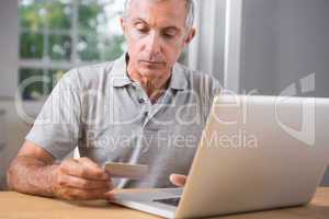 Thoughtful mature man using his laptop