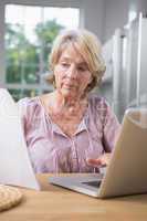 Focused mature woman using her laptop