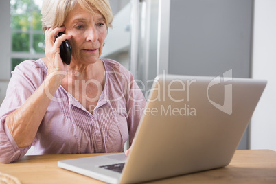 Focused woman using her laptop and calling