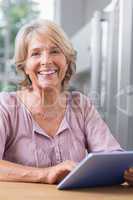 Happy mature woman using her digital tablet