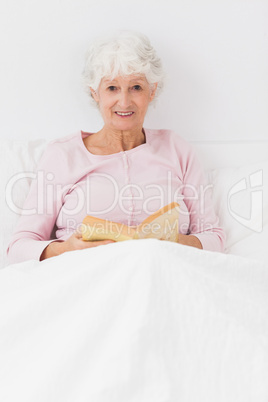 Smiling woman reading in bed Smiling woman reading in bed