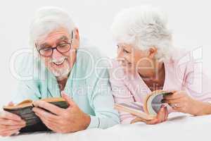 Happy husband and wife reading in bed