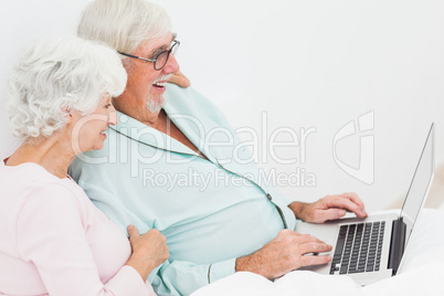 Couple with laptop in bed Couple with laptop in bed