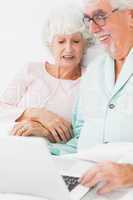 Smiling couple using laptop in bed