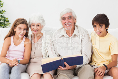 Smiling grandparents with grandchildren reading