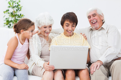 Grandparents and grandchildren using laptop