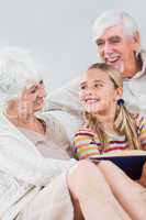 Happy grandparents reading with granddaughter