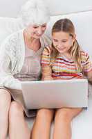 Smiling girl using laptop with granny