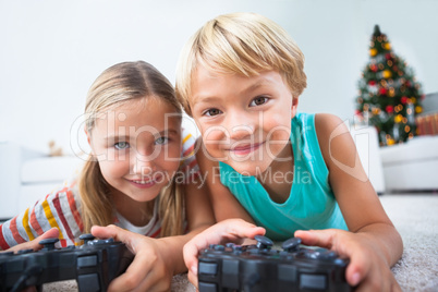 Happy siblings playing video games on floor