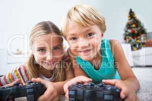 Happy siblings playing video games on floor