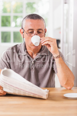 Man reading newspaper and drinking espresso