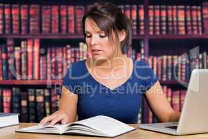 Woman reading book with computer