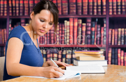 Cute girl writing on notebook in library