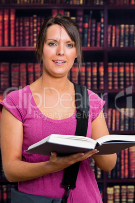 Smiling woman with a book in library