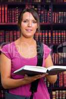 Smiling woman with a book in library