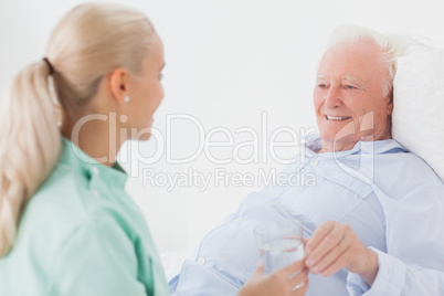 Home nurse giving man glass of water