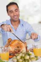Man carving turkey at head of table