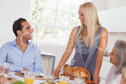 Happy wife bringing turkey to the table