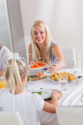 Mother handing carrots to daughter at dinner