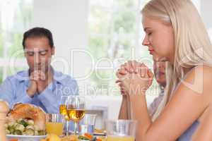 Woman saying grace with family before dinner