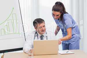 Doctor showing nurse something on laptop