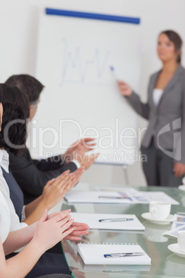 Businesswoman explaining and her colleagues clapping